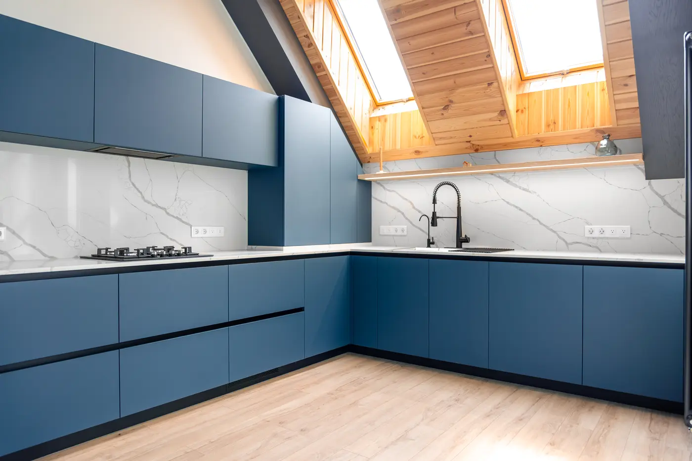 L-shaped kitchen with matte blue cabinets, white marble backsplash and skylights