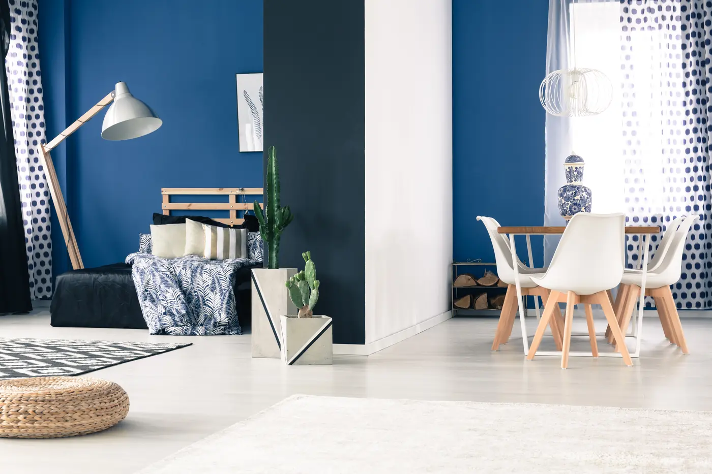 Open living space with cobalt blue walls, a charcoal partition wall and white dining chairs
