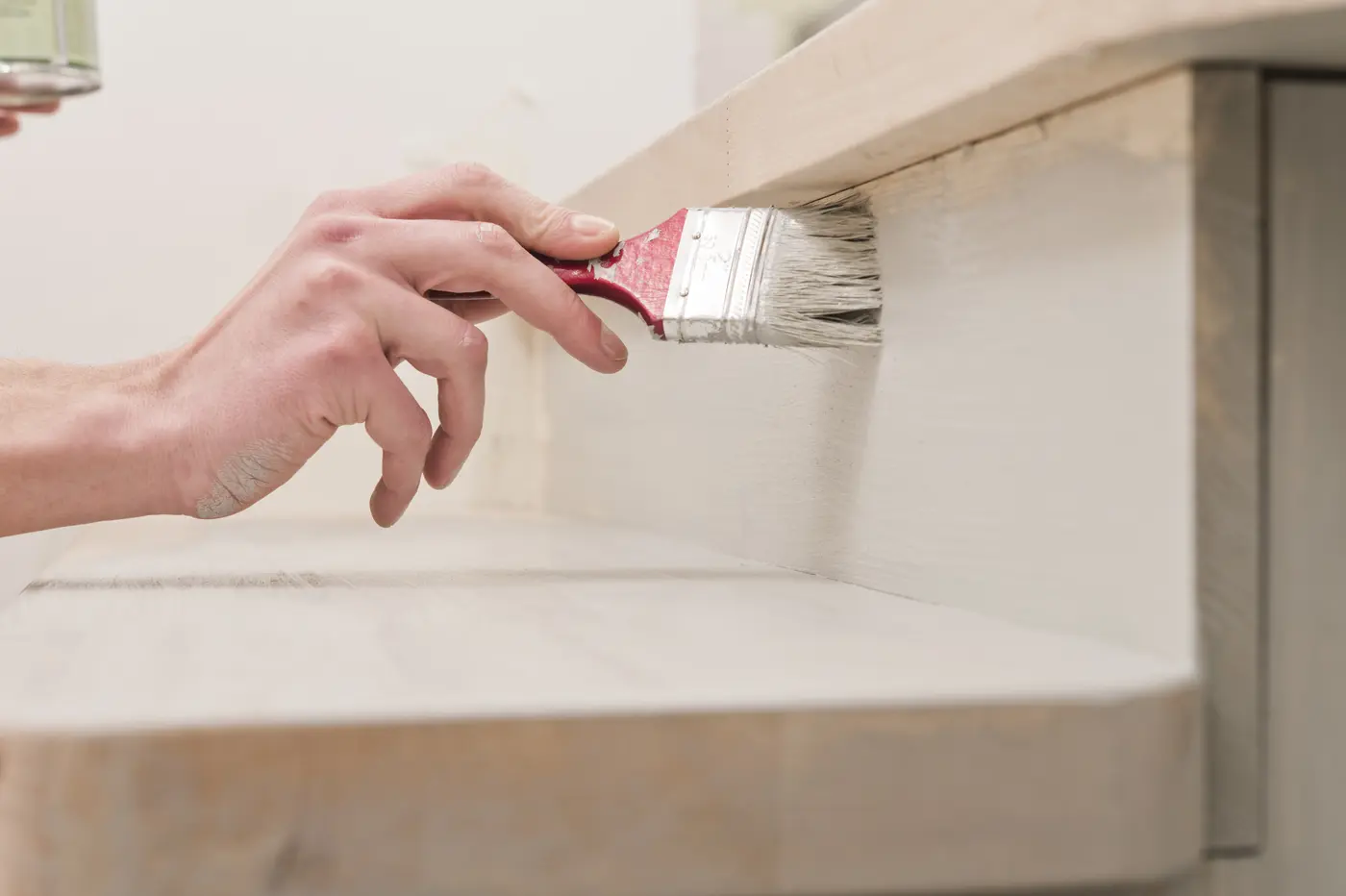 Brushing white paint onto built-in shelving