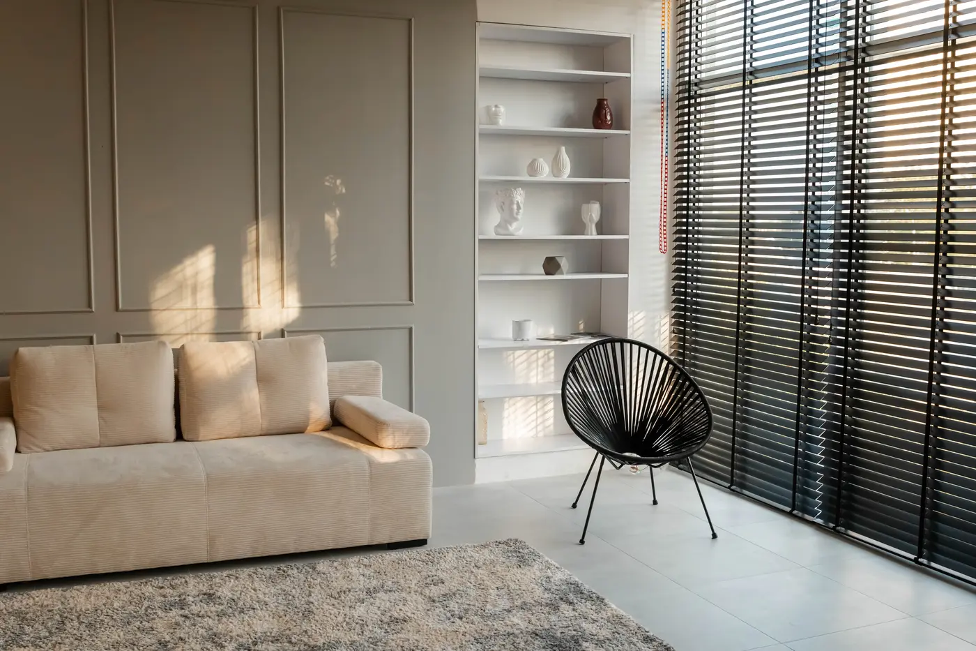 Greige living room wall with applied box molding, built-in white shelves and a beige sofa