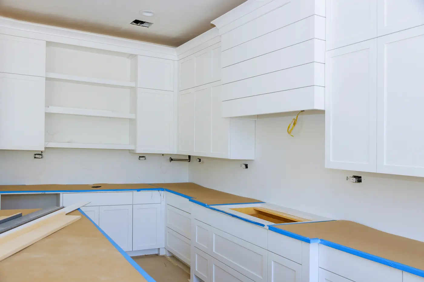 New white shaker cabinets with countertops covered in paper and blue painter's tape