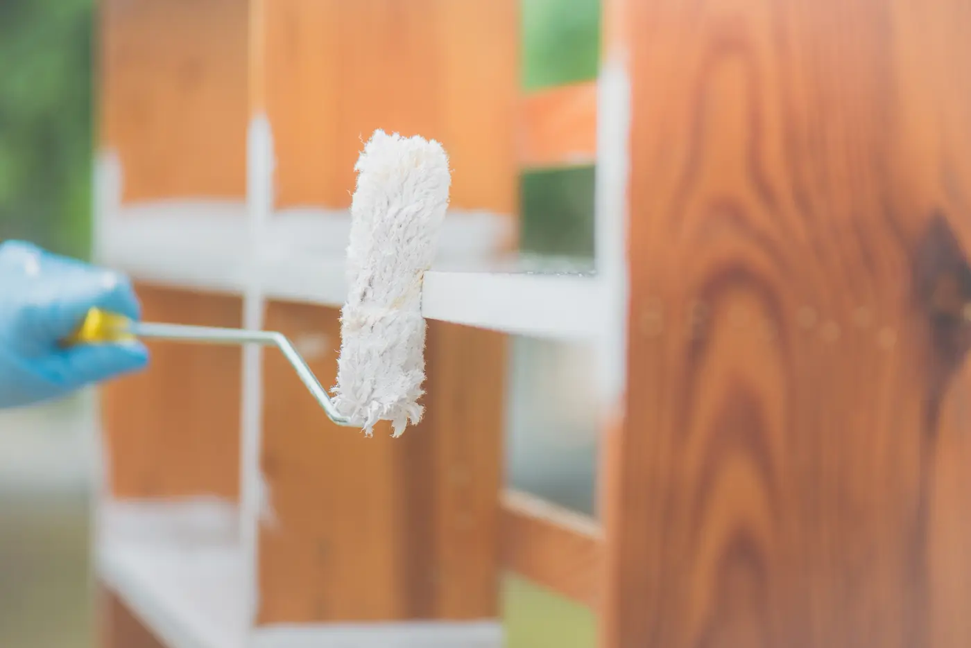 Rolling white paint over a stained wood cabinet frame