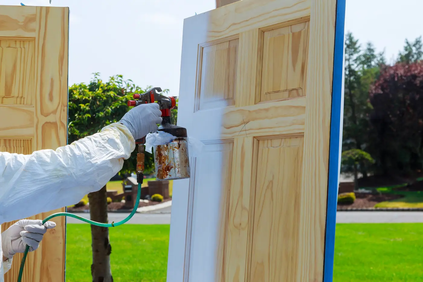 Spraying white paint onto a paneled wood door