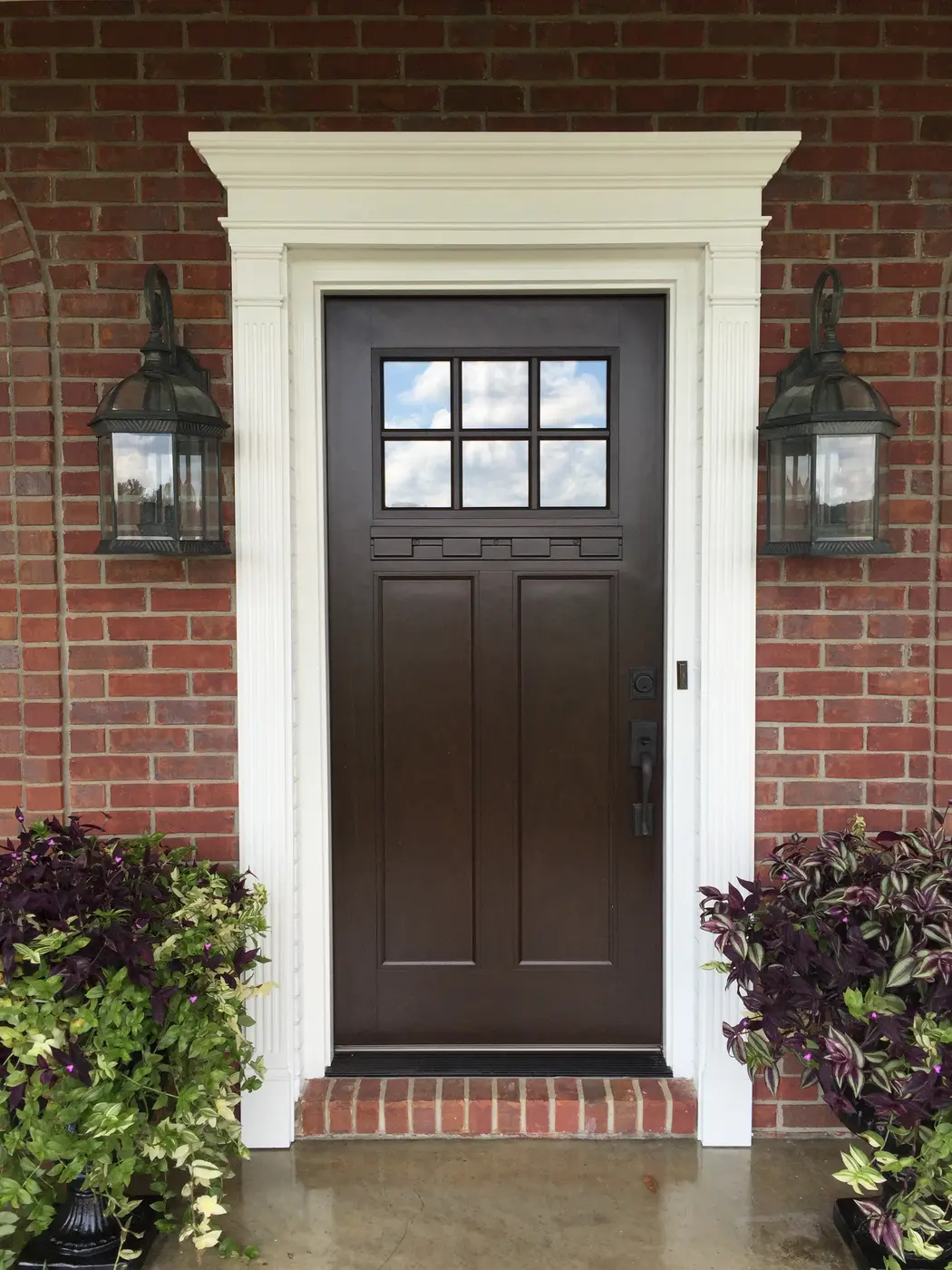 Dark stained front door framed by white painted casing
